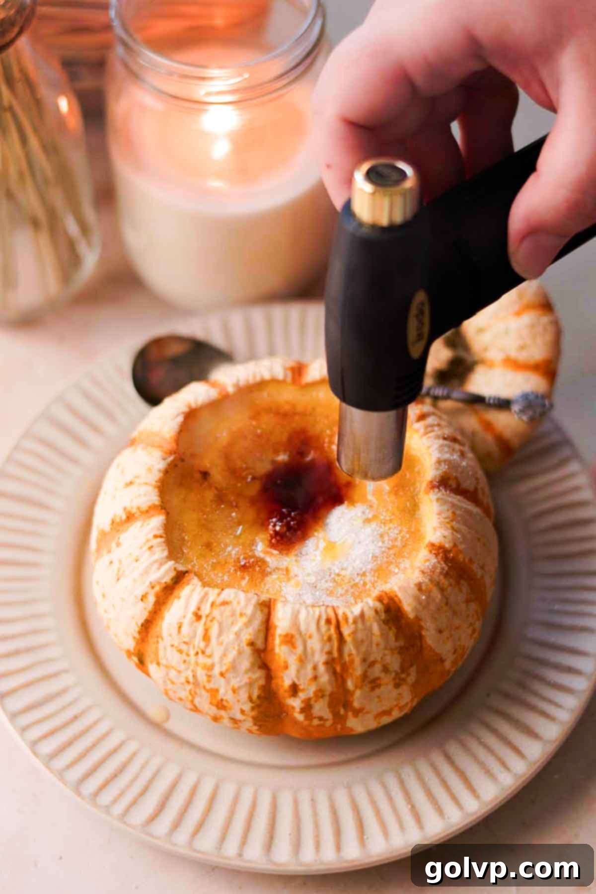 torching top of creme brulee inside of pumpkin with a kitchen torch