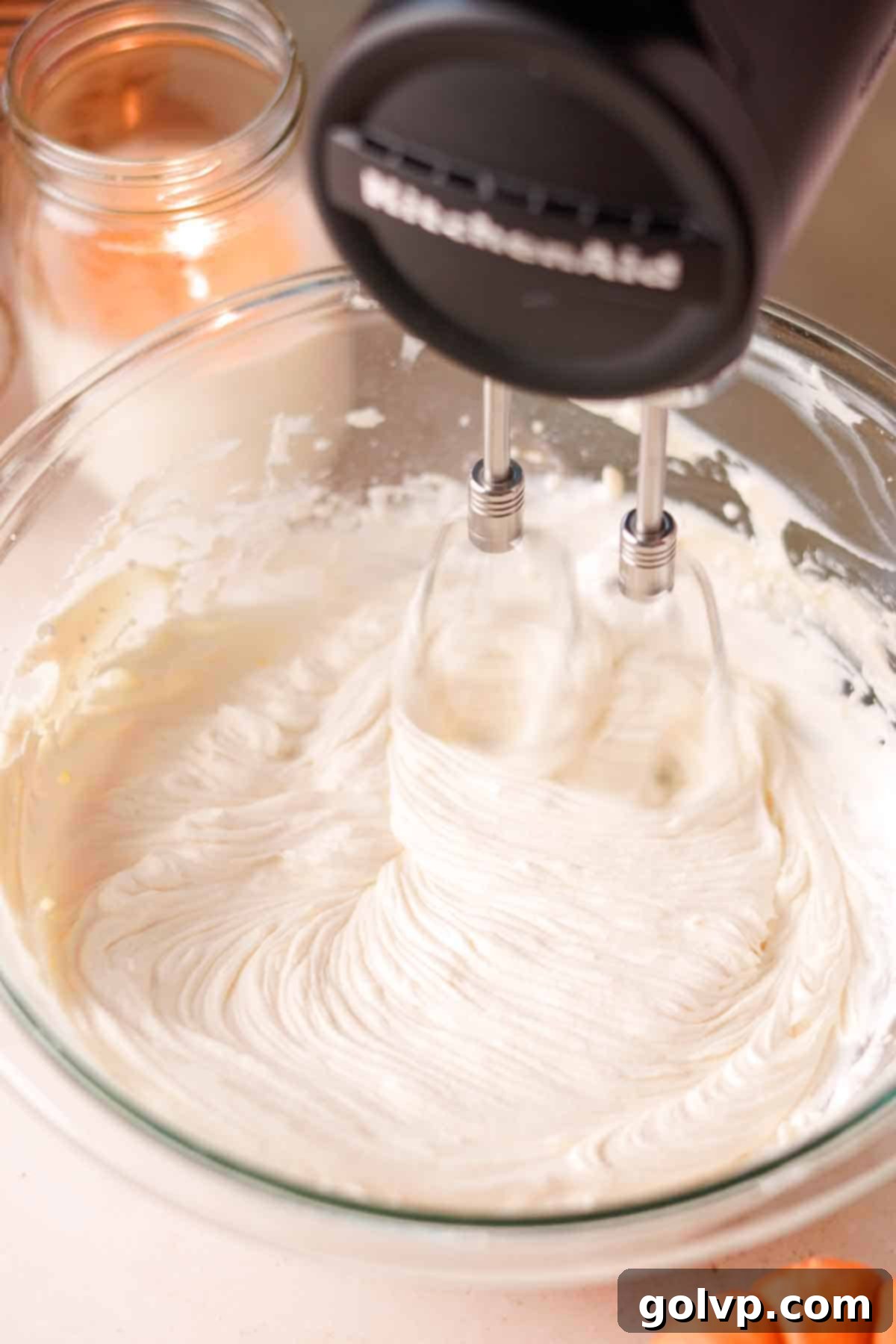 Adding fluffy whipped cream to the rich cream cheese mixture, ready to be beaten together for a stiff, creamy cheesecake filling.