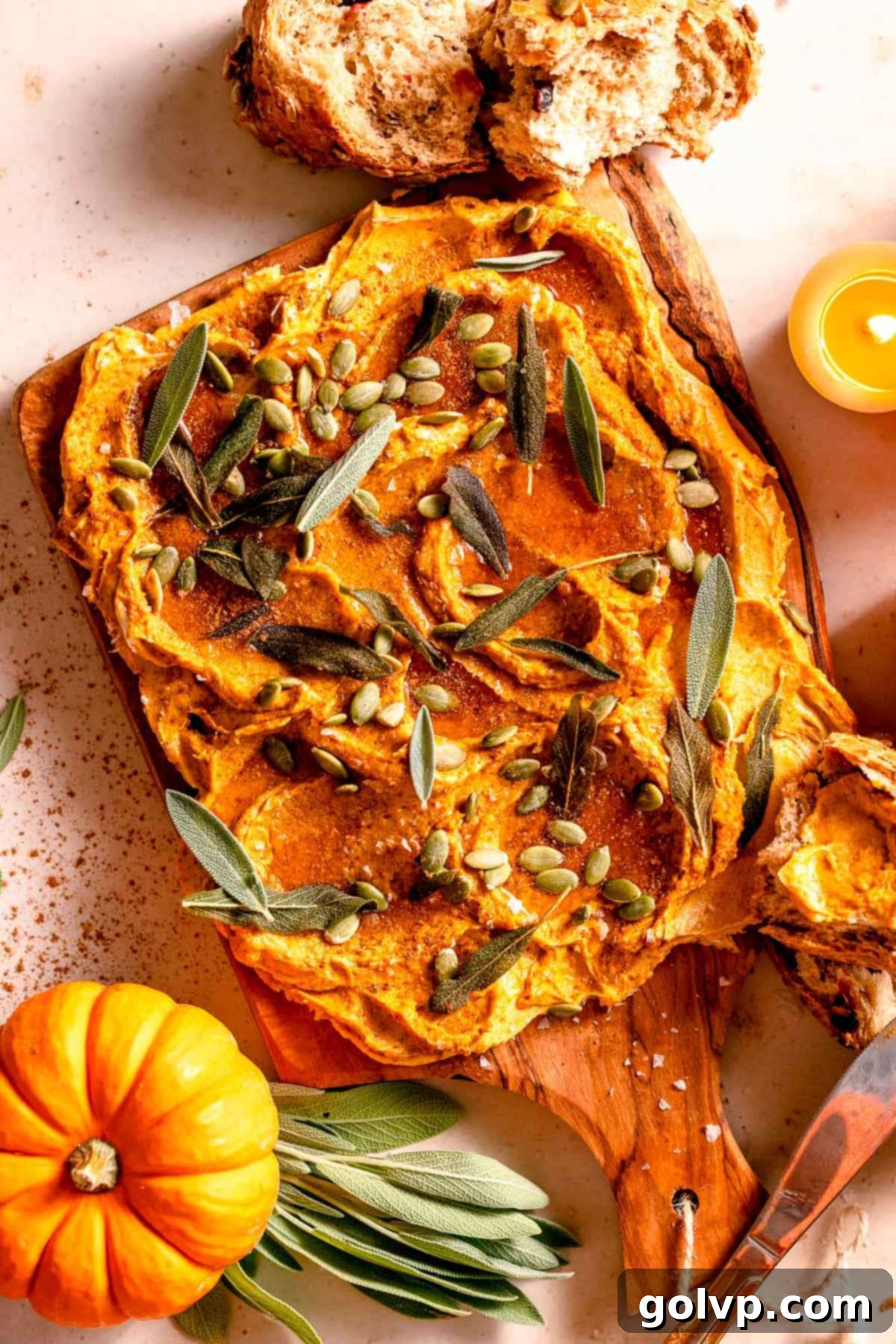 Pumpkin infused butter spread on a board with sage leaves and mini pumpkins