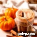 Iced coffee topped with pumpkin cold foam and spoon with mini pumpkins surrounding