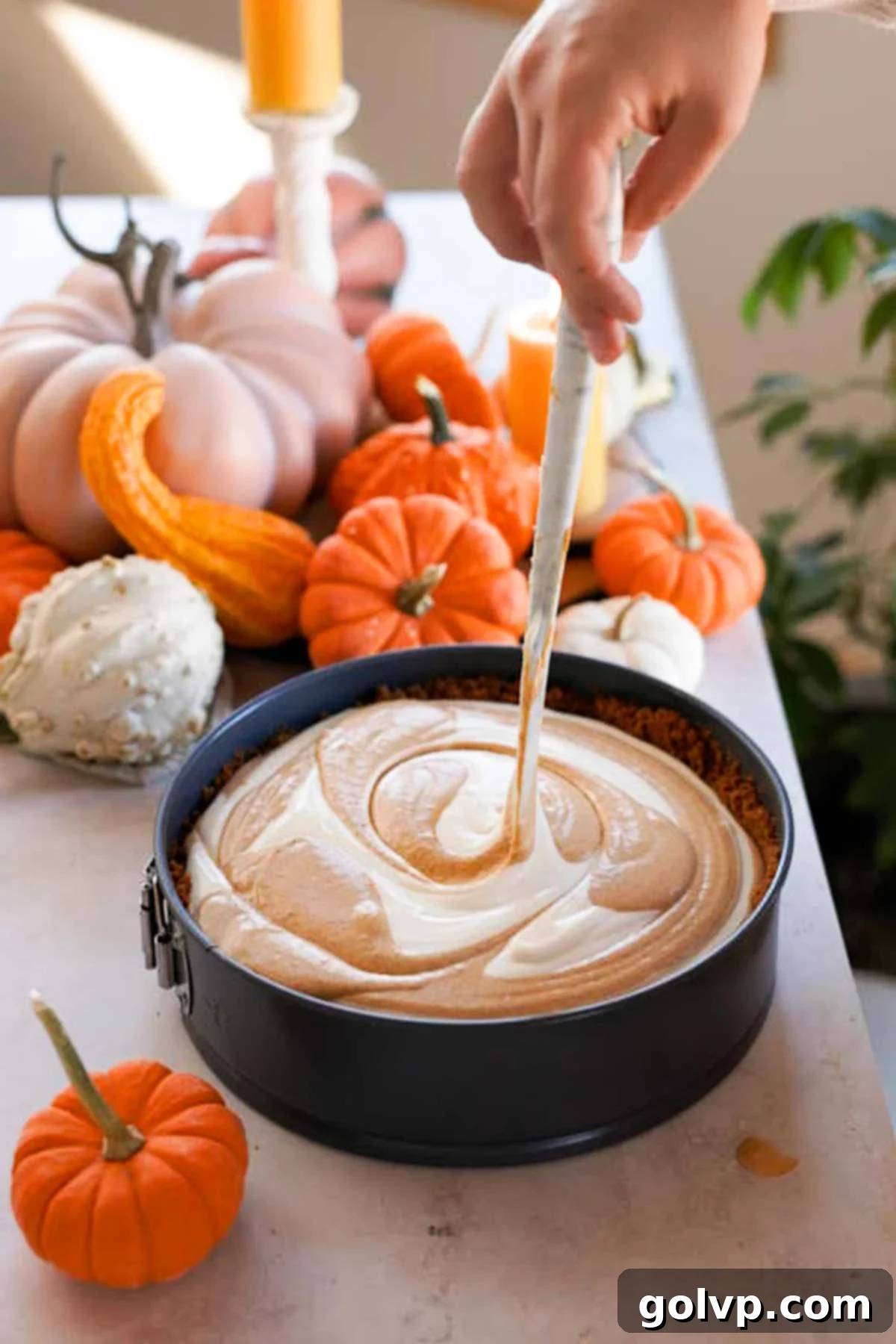 swirling pumpkin pie cheesecake with a spatula
