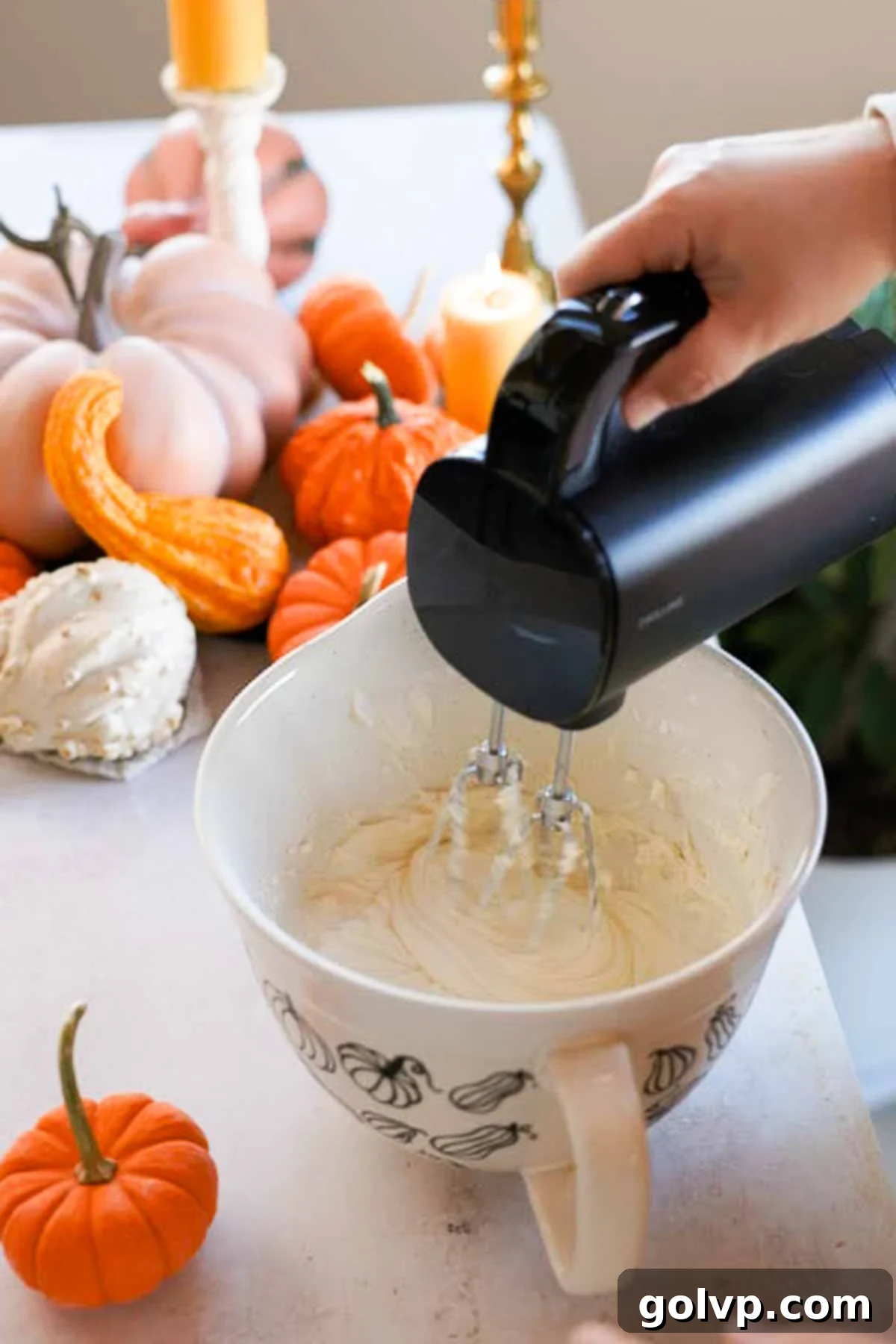 mixing cream cheese and sugar with an electric mixer in a large bowl