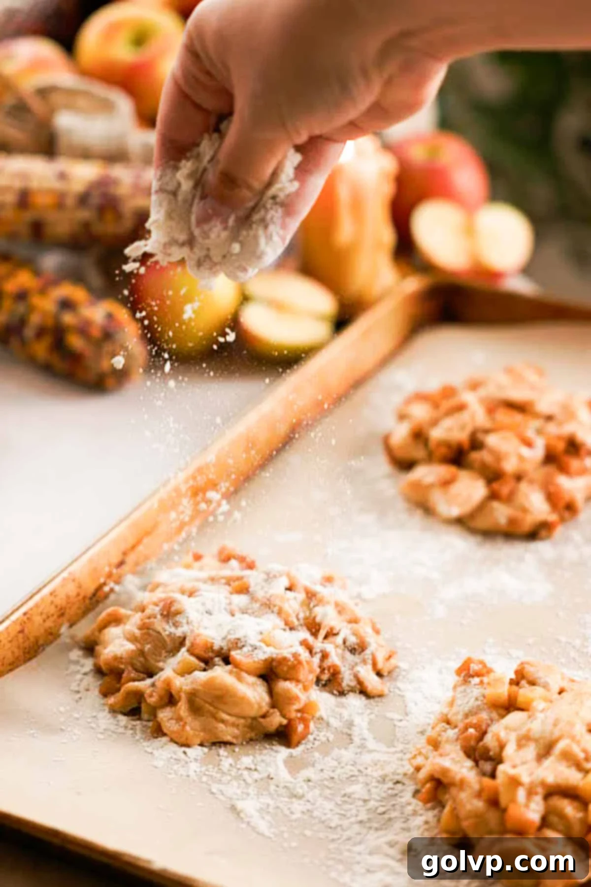 sprinkling shaped apple fritters on parchment paper with flour