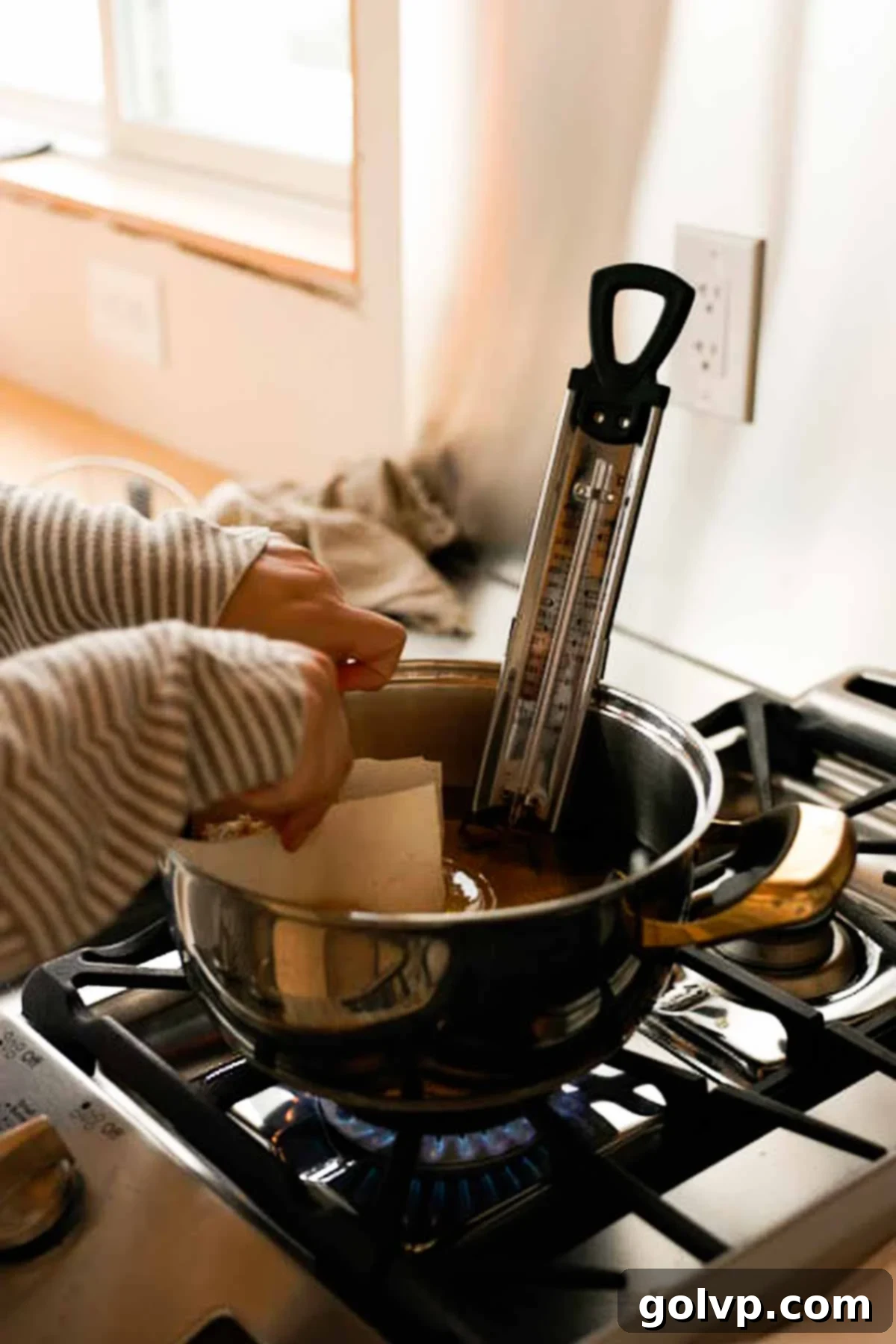 dropping apple fritters into hot oil on parchment paper
