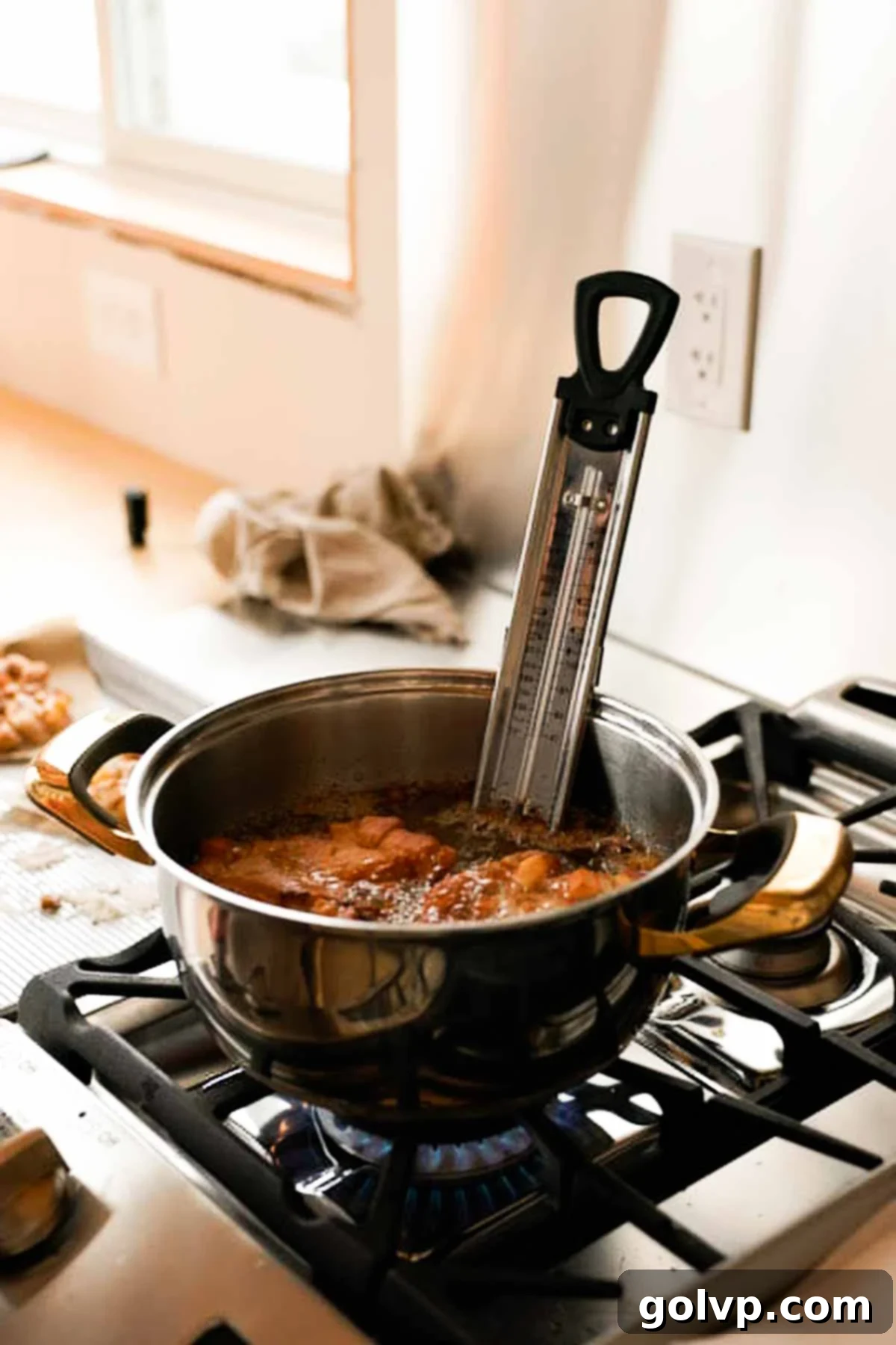frying apple fritters in a pot filled with hot oil and a candy thermometer