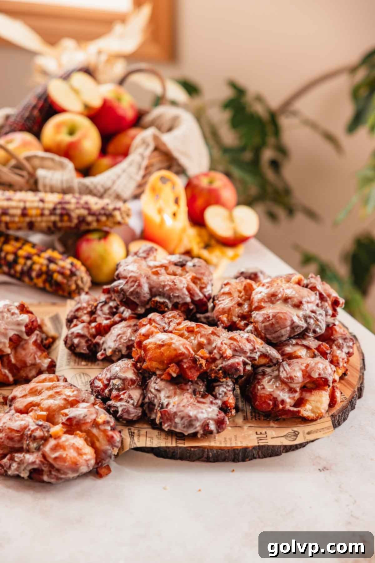pile of glazed apple fritters on a wooden tray