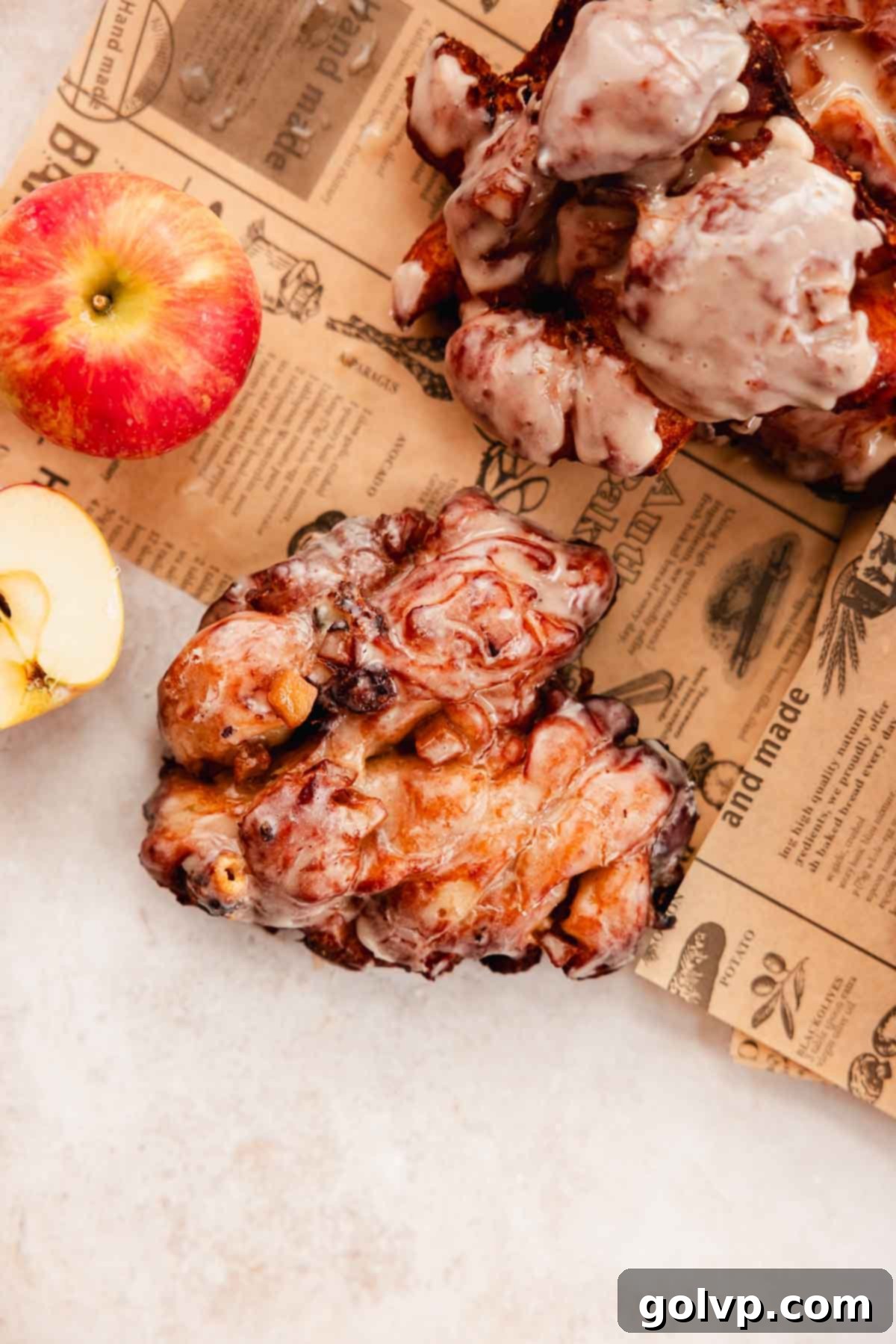 fried apple fritter with glaze on piece of parchment paper