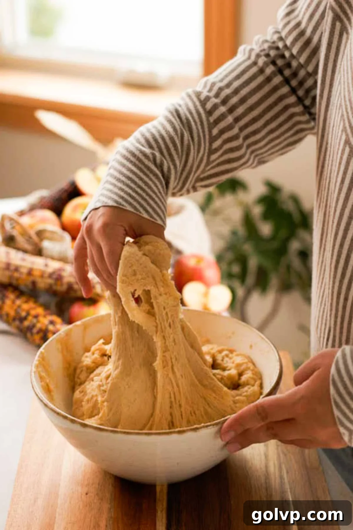 folding risen apple fritter dough inside bowl