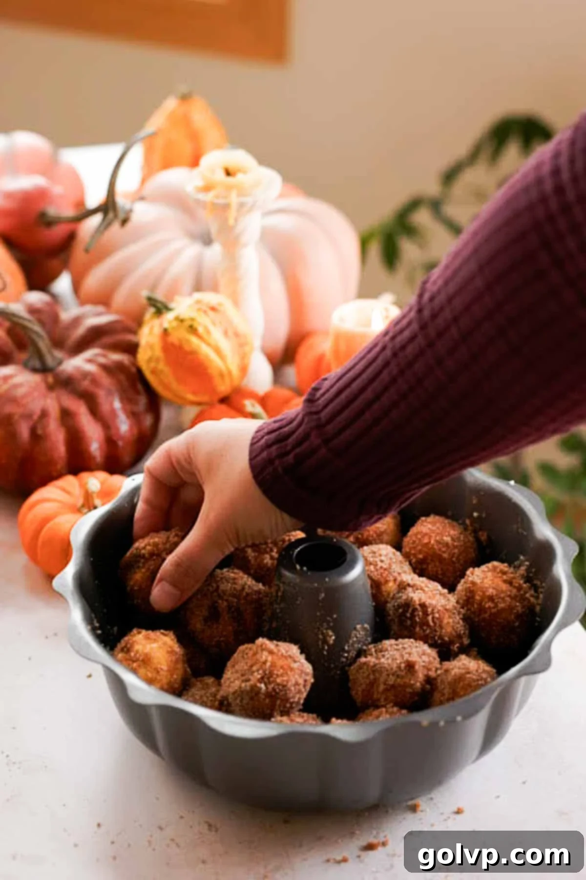 Layered pumpkin monkey bread dough balls neatly arranged in a bundt pan, ready for baking.