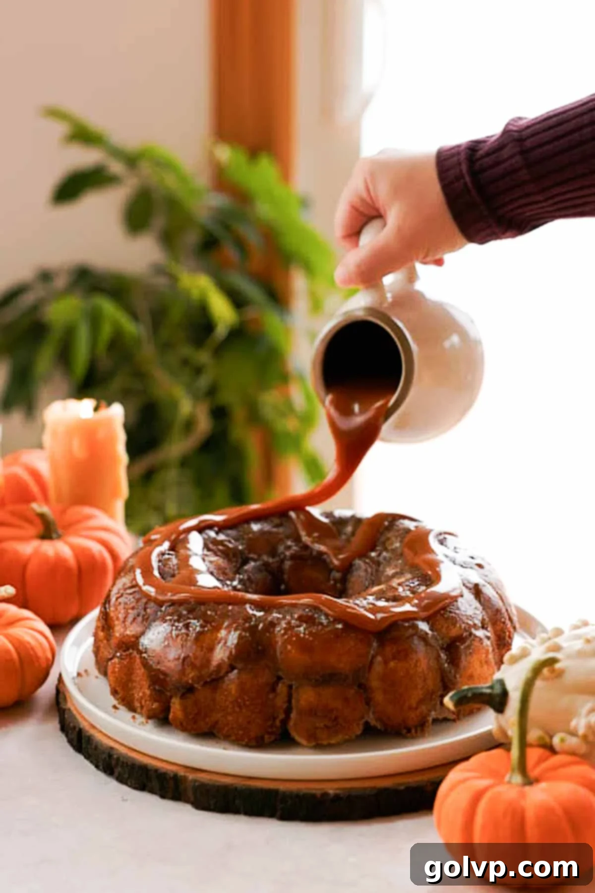 Generous drizzle of warm caramel sauce over a freshly inverted pumpkin monkey bread on a serving platter.