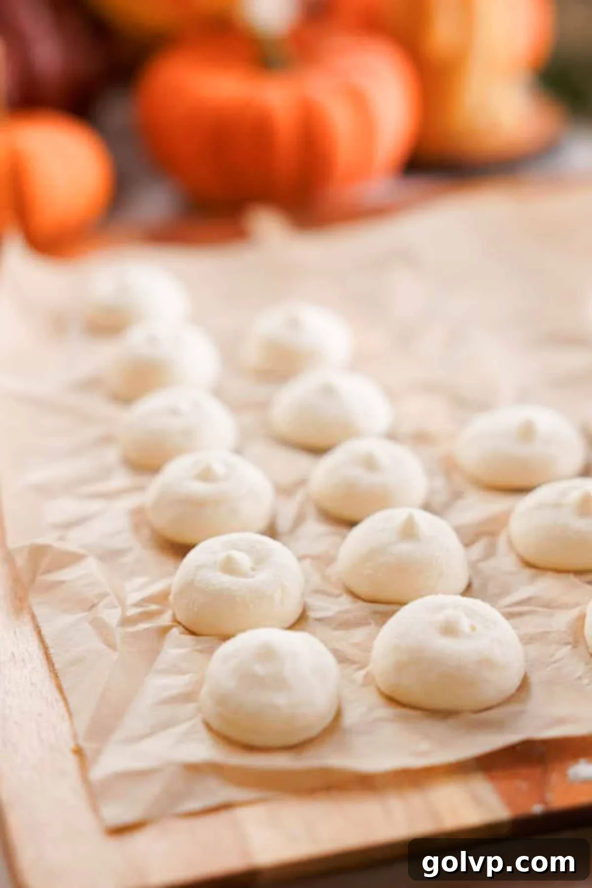 Small dollops of cream cheese filling, frozen solid on parchment paper, ready to be stuffed into dough.