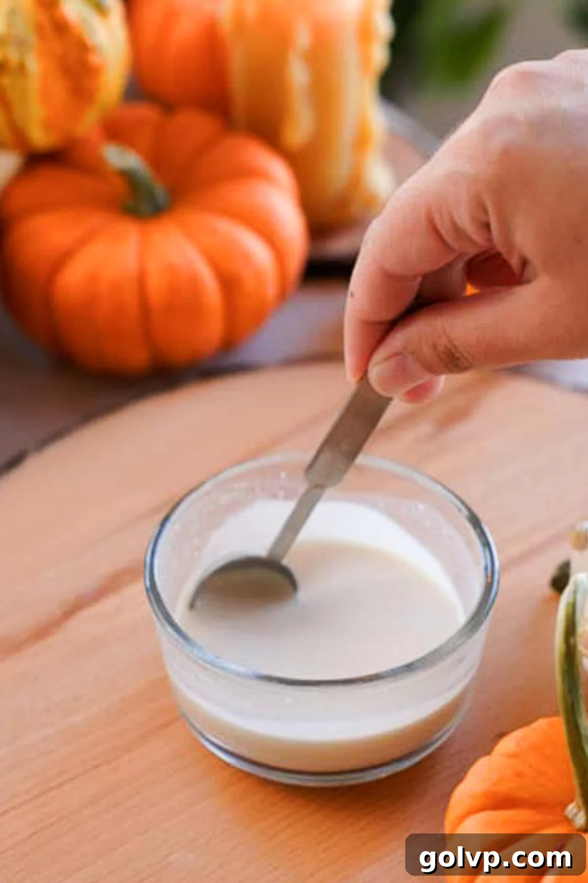 Close-up of active dry yeast being stirred into warm water with a spoon, showing a foamy surface.