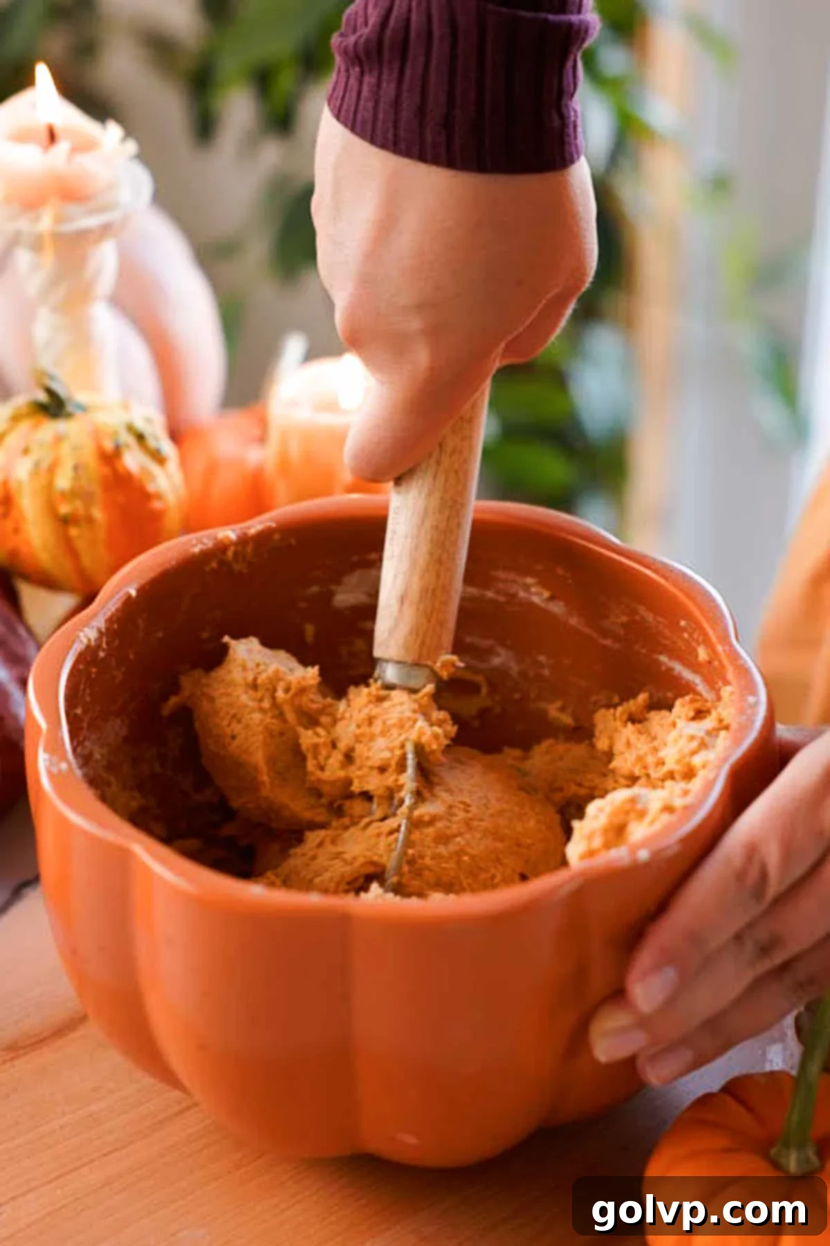 A Danish dough whisk mixing soft pumpkin monkey bread dough in a large bowl.